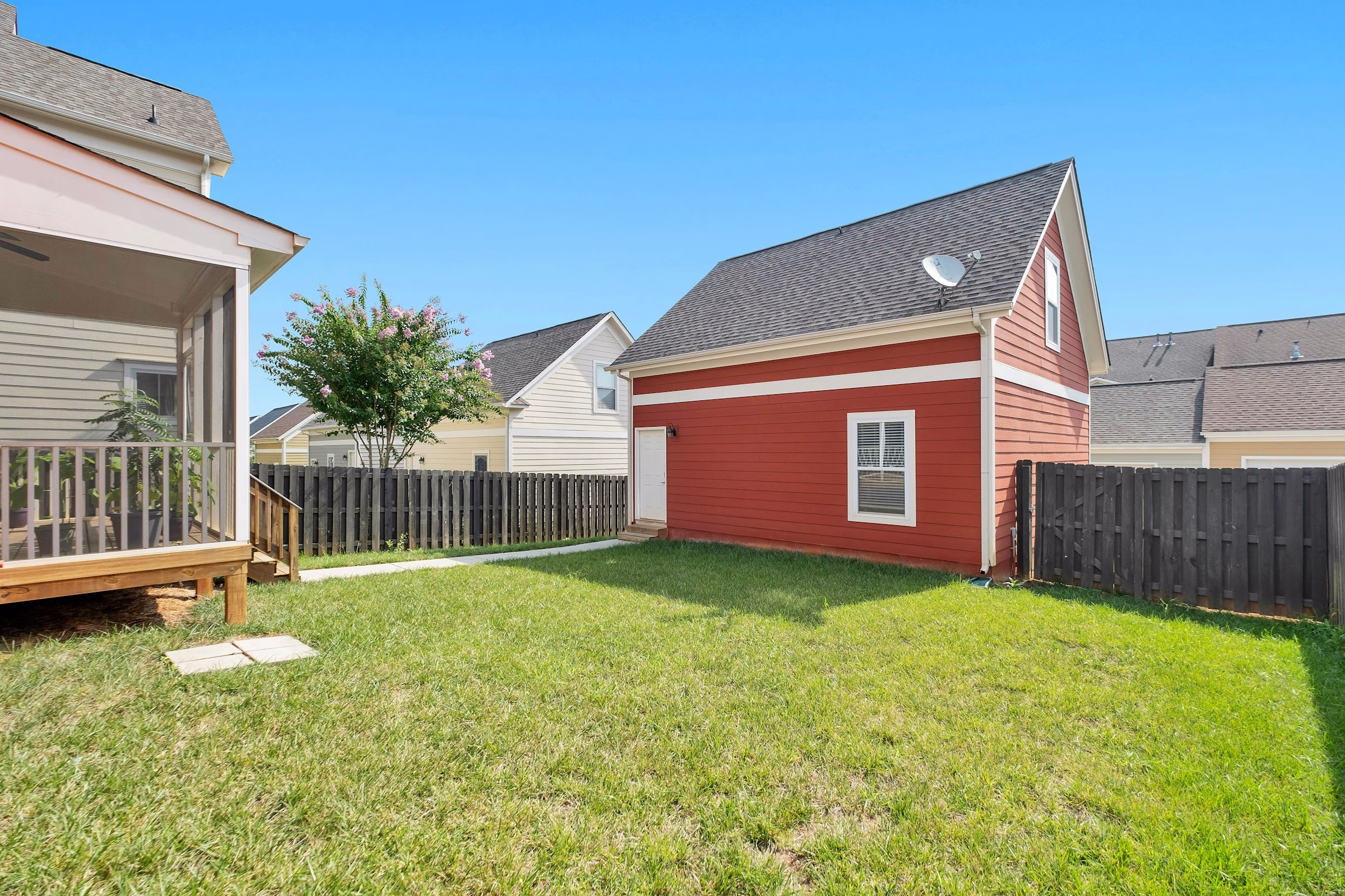 Low-angle view of a backyard lawn with fence and trees - prime tick habitat